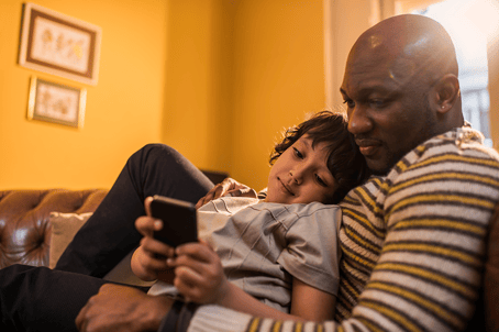 Dad and child on sofa looking at phone