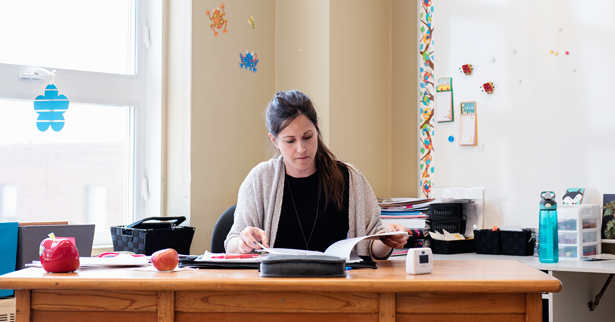 Teacher sitting at desk working on student reports