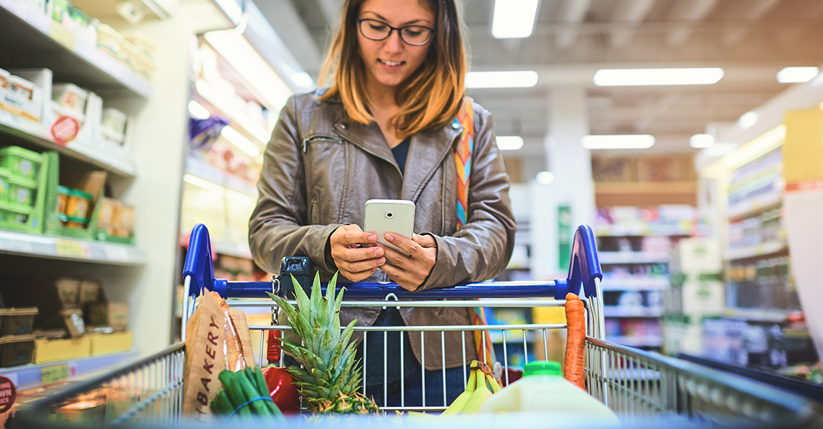 Woman looking at mobile phone in supermarket